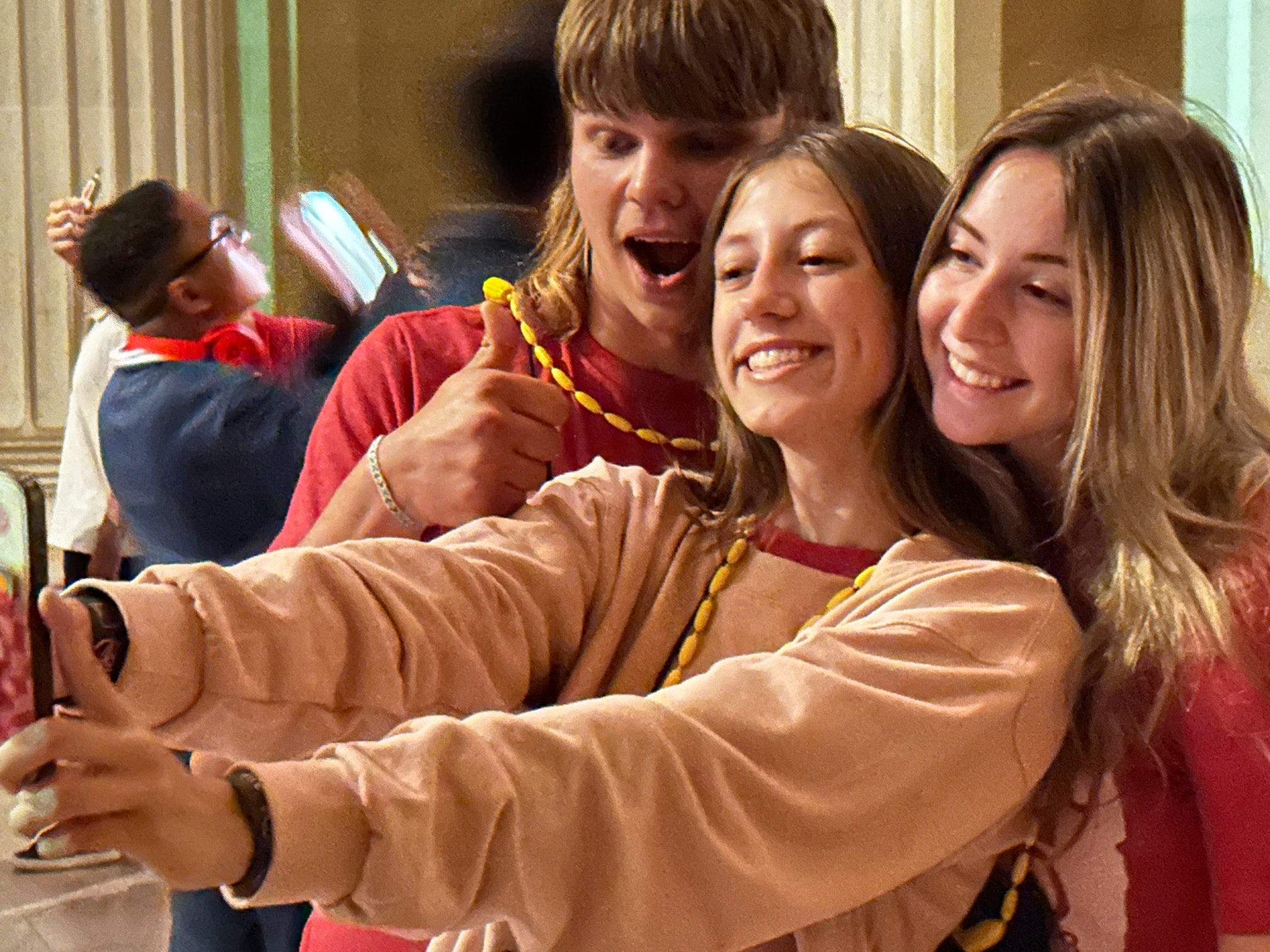 two teenage girls and one teenage boy taking a selfie