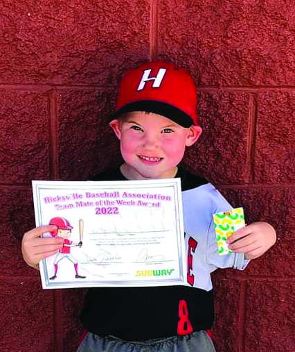 young boy in baseball cap holding certificate