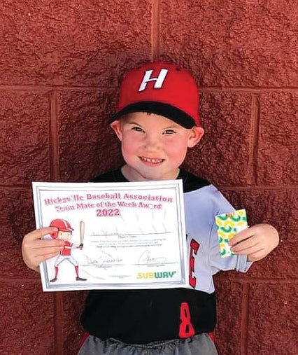 young boy in baseball cap holding certificate